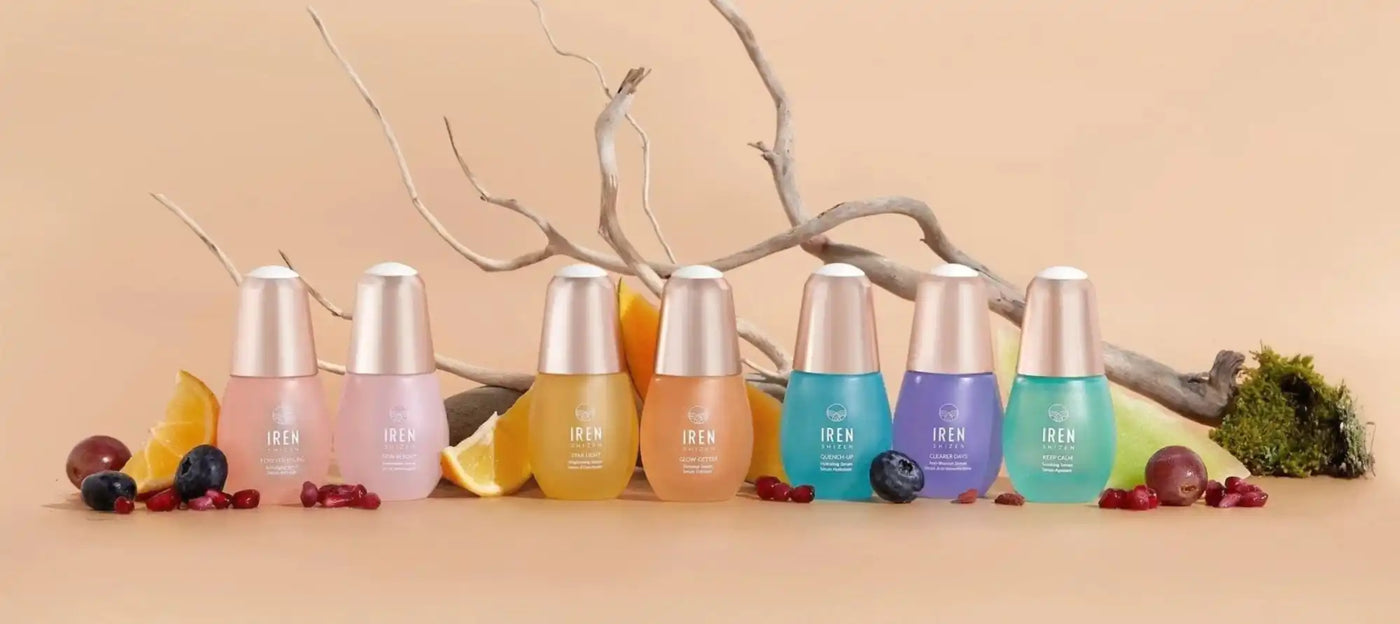 Hét színes kozmetikos üveg sor, mindegyikhez különféle friss gyümölcsök és bogyók társítva.