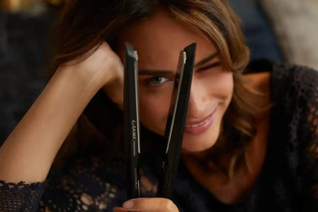 Egy nő, aki egy fekete hajvasalót tart.